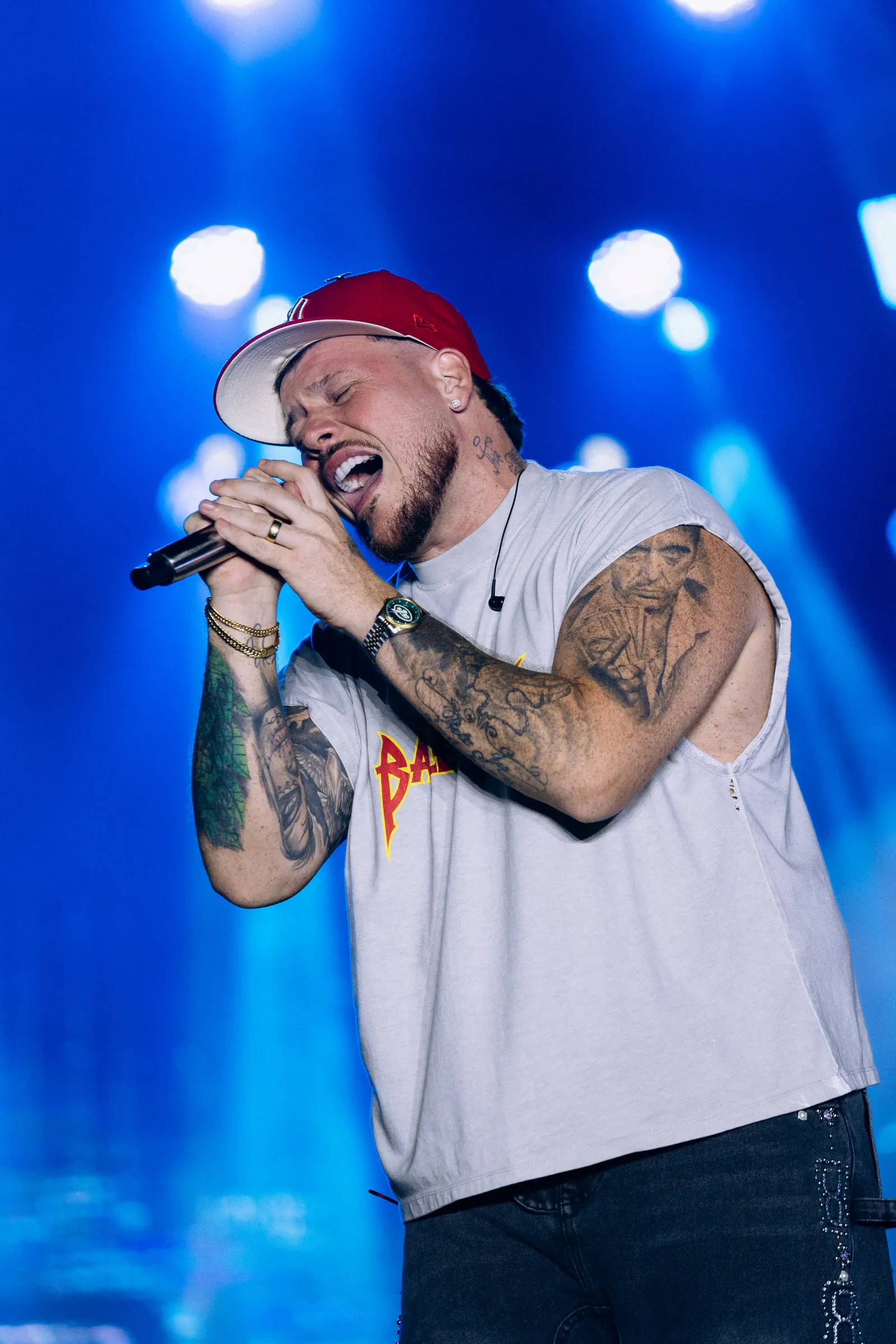 Festival de Verão Cabo Frio — Cantor de boné no microfone sob iluminação azul